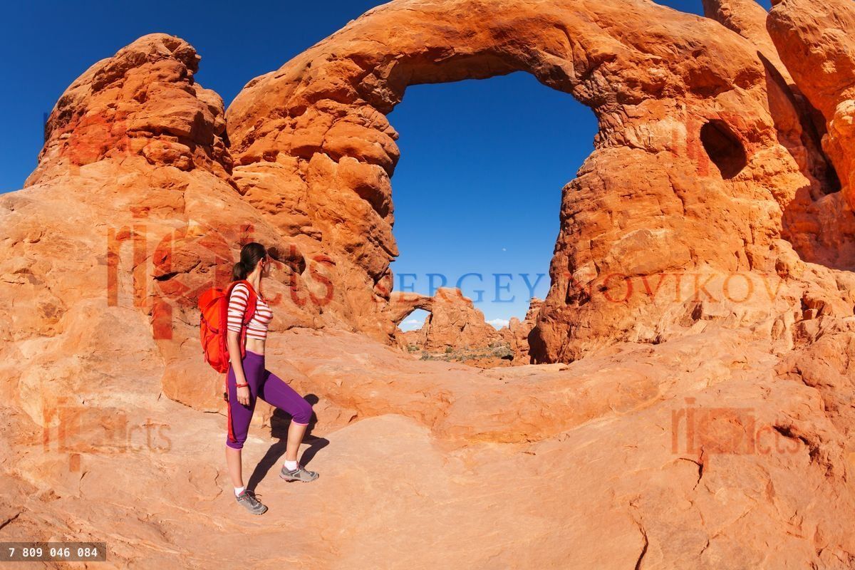 Woman with bag walks to beautiful arches Utah