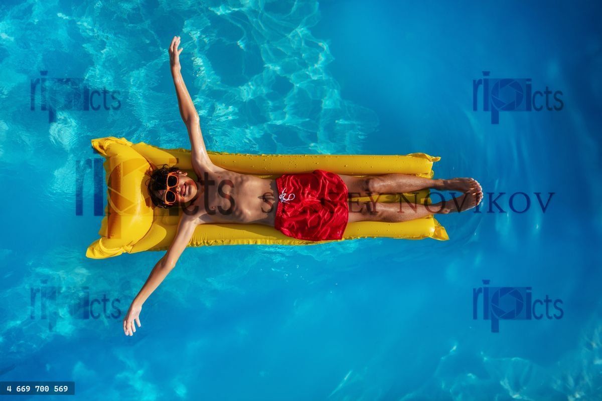 Boy chilling on a yellow raft in water view from above