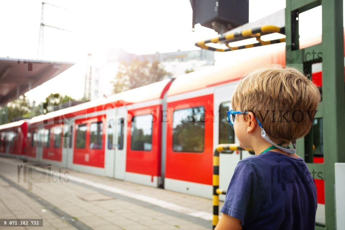 Young boy standing on a railroad platform looking at metro train
