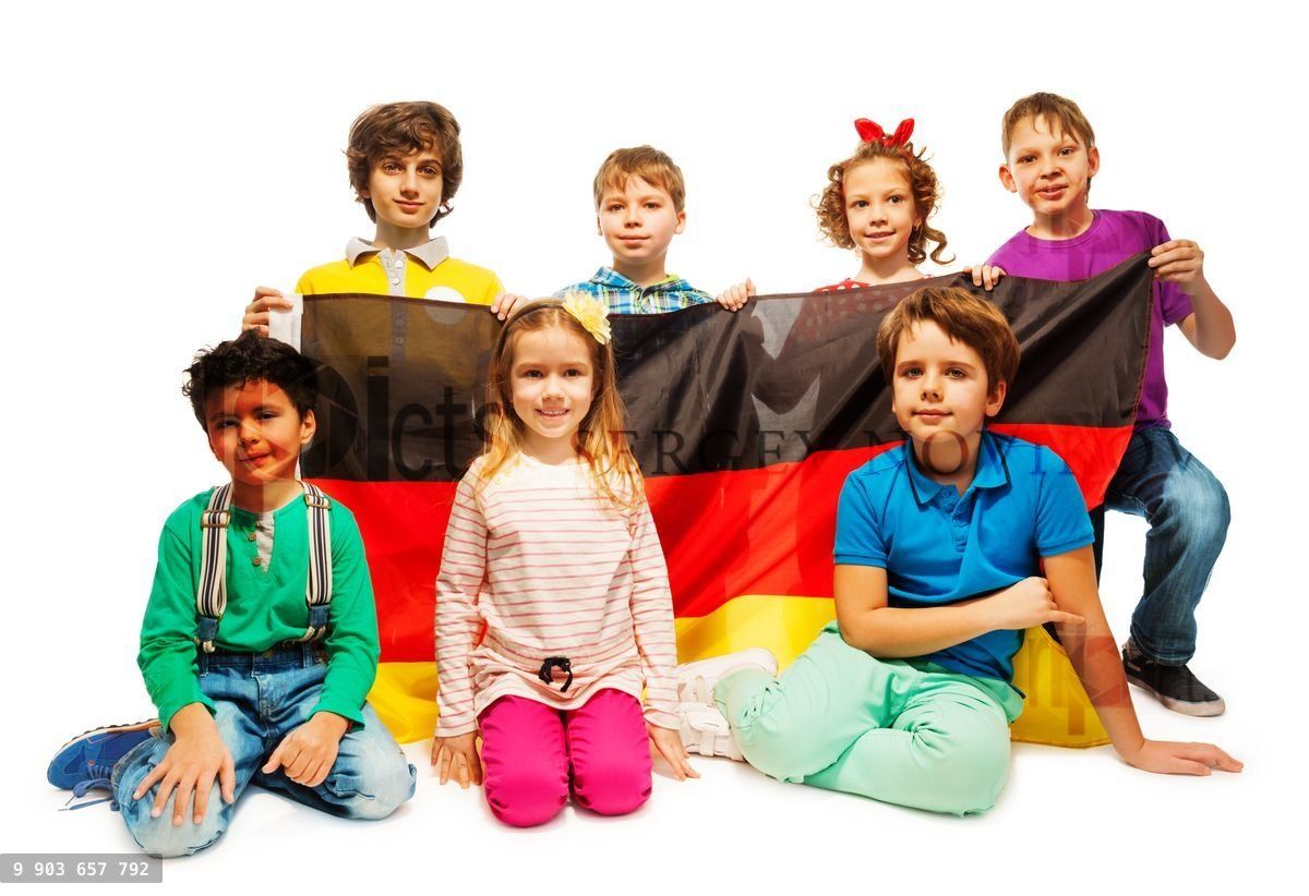 Group of seven children sitting with a German flag