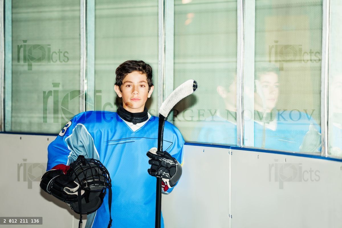 Young hockey player with helmet and stick at rink