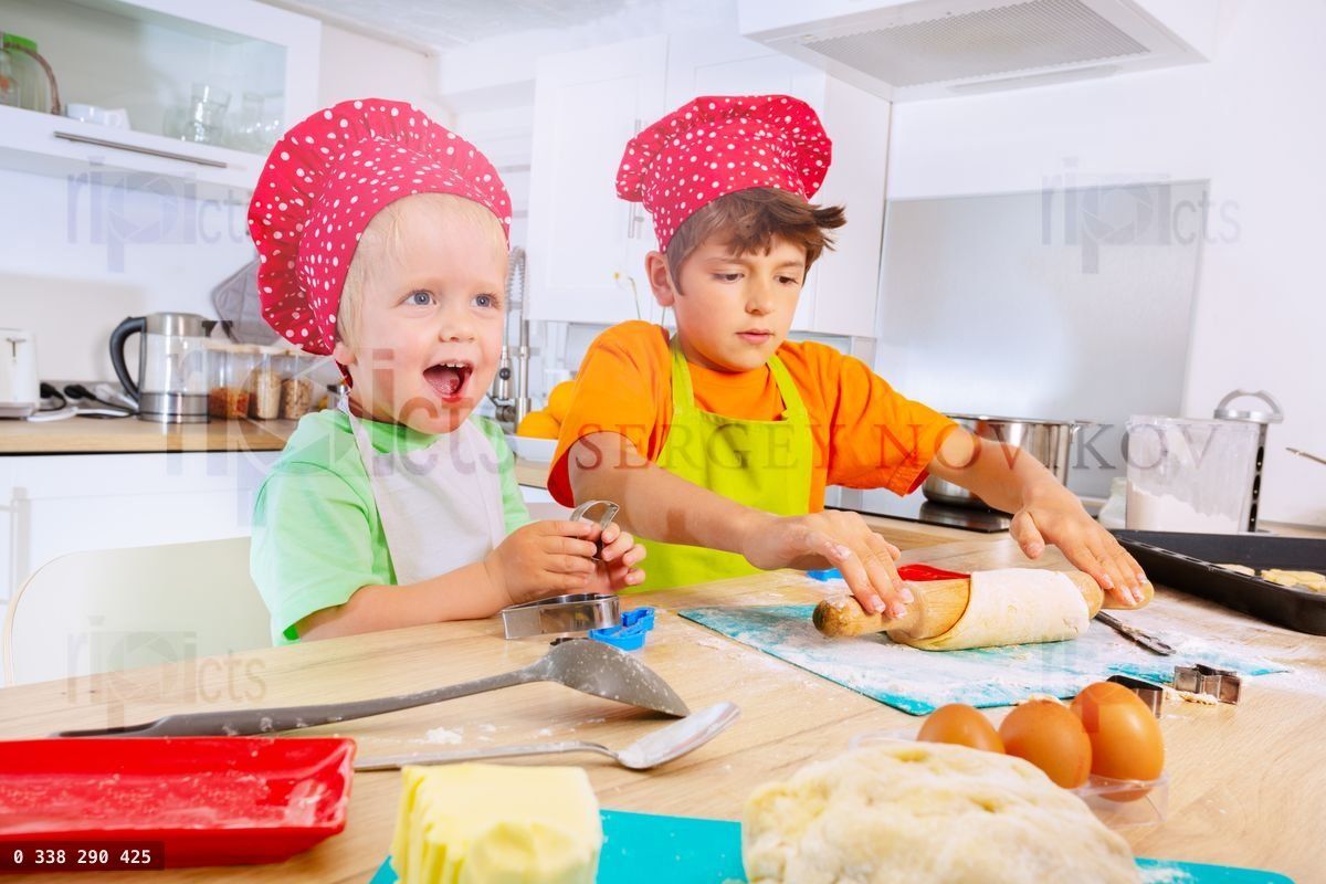Cute toddler with brother make cookies at kitchen