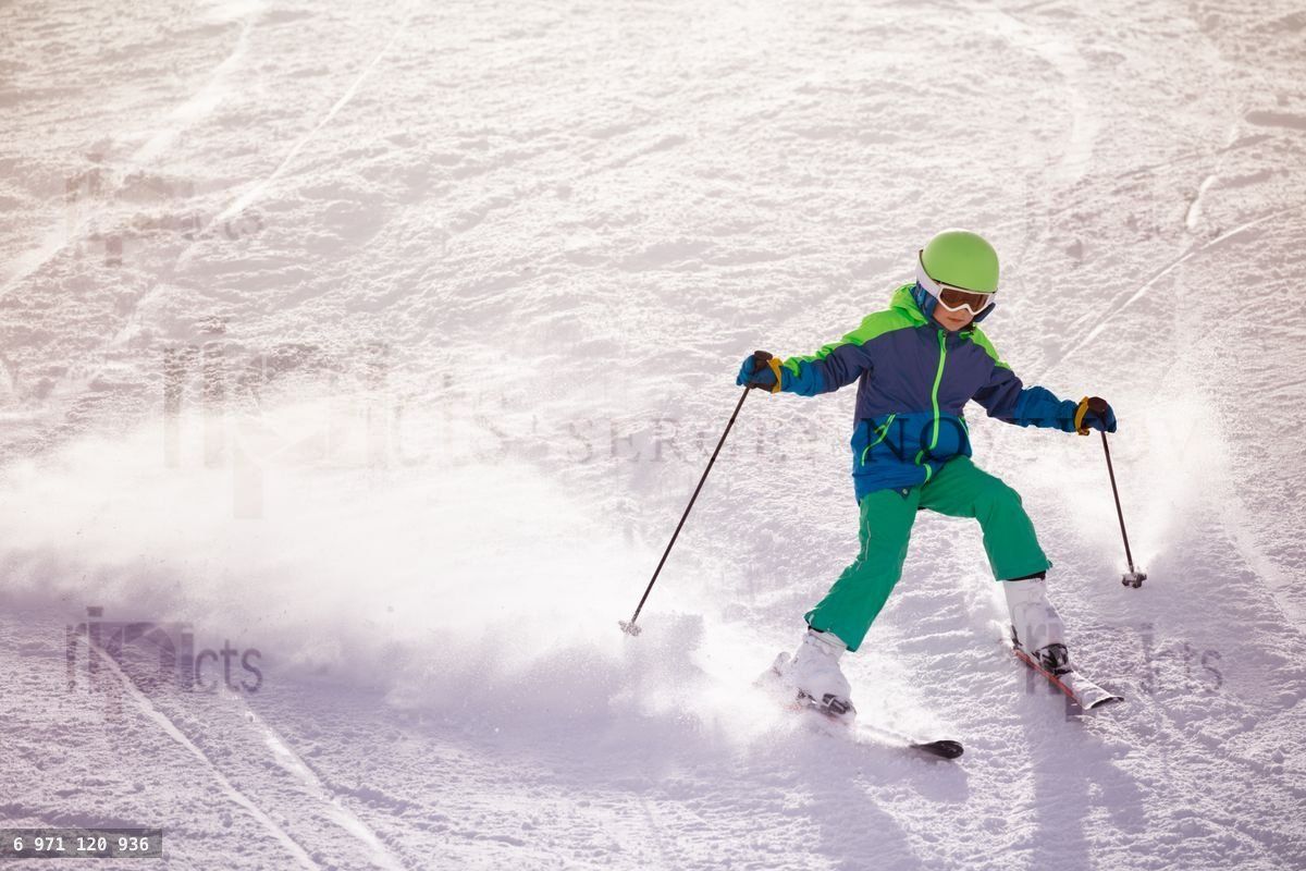 Little boy ski fast downhill on the mountain slope