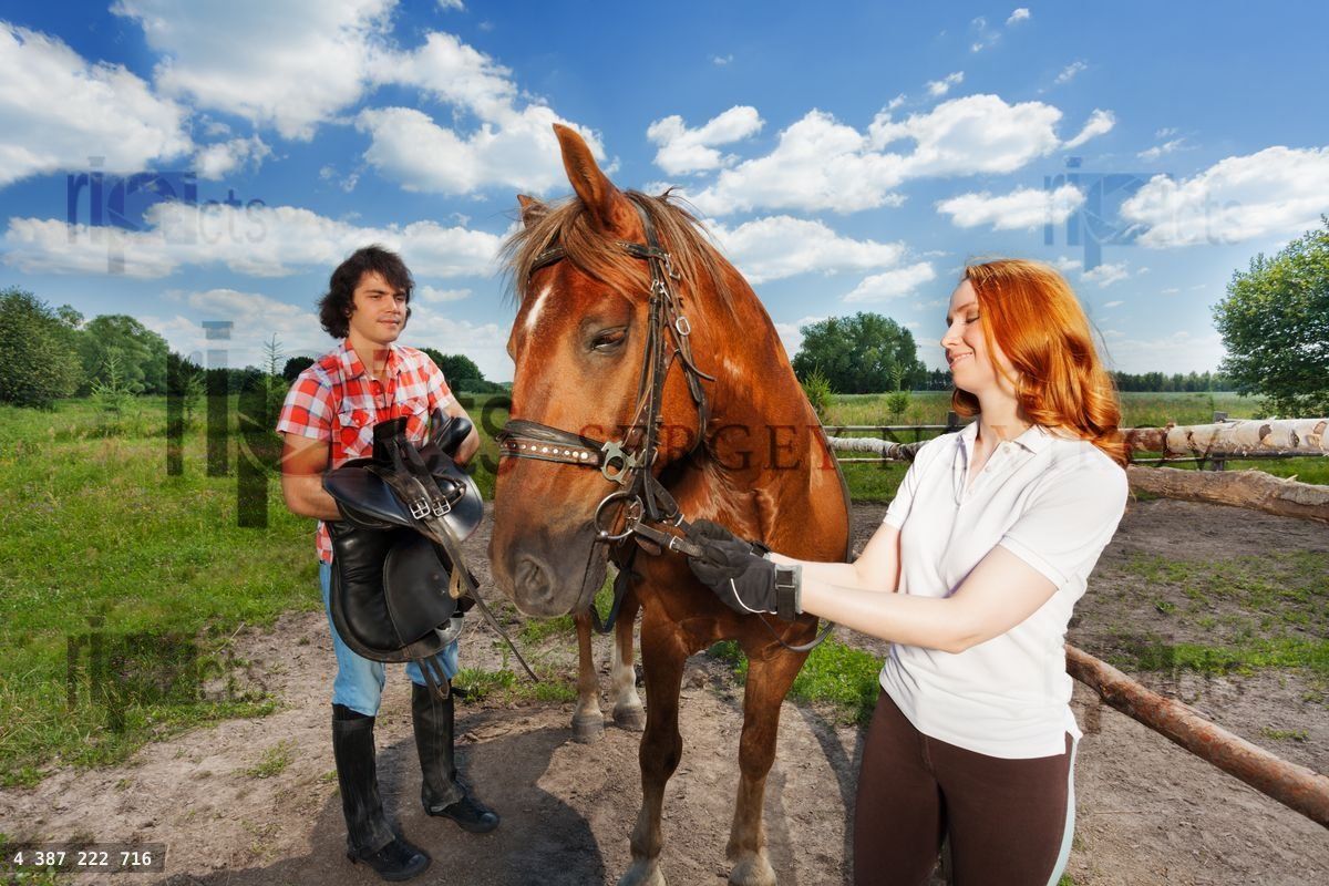 Young couple preparing for horseback ride at farm