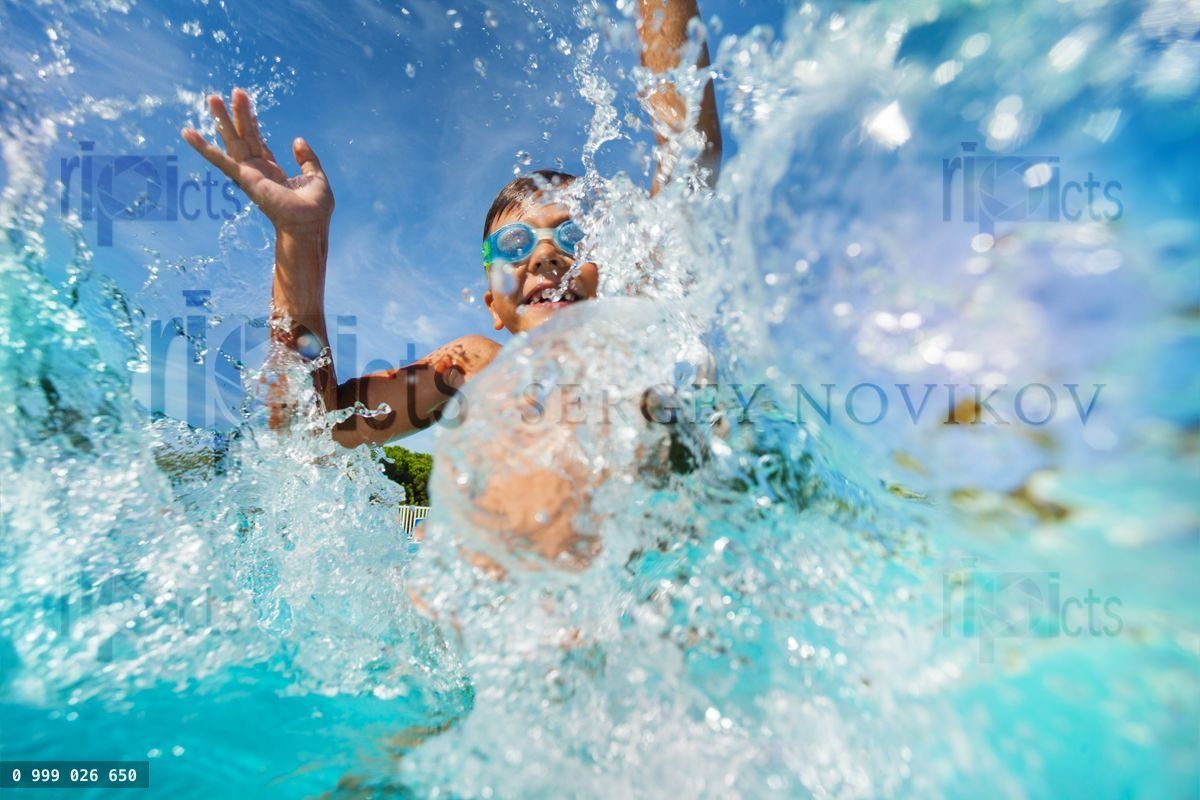 Happy boy playing and splashing in swimming pool