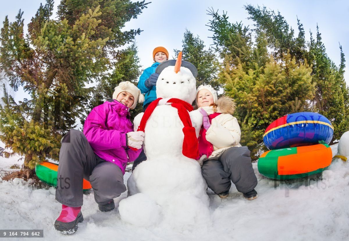 Vue d'en bas d'enfants assis près d'un bonhomme de neige