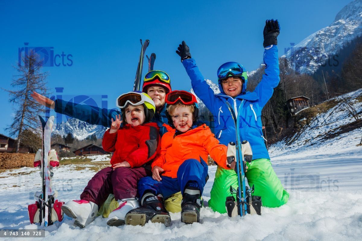 Mère et enfants s'amusant en vacances au ski, assis dans la neige avec des skis