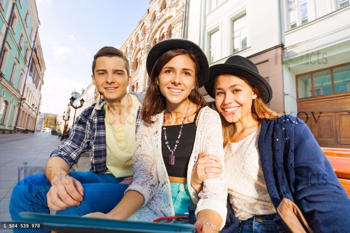 Friends sit on the bench together holding tablet