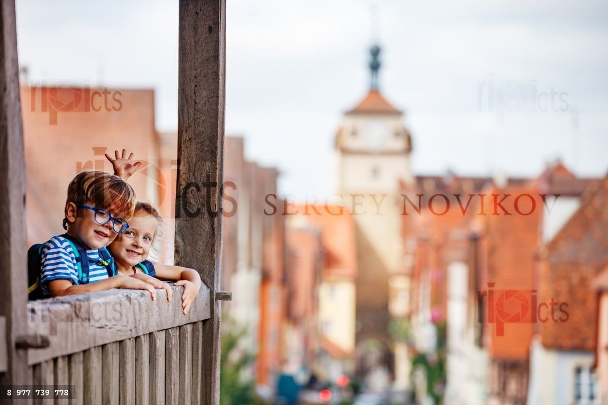 Girl and boy enjoying old town scenic view from a wooden balcony