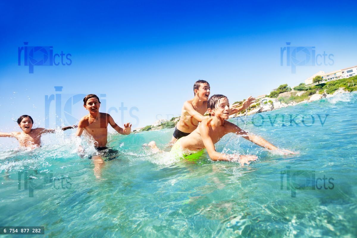 Four happy teenage boys swimming in the sea