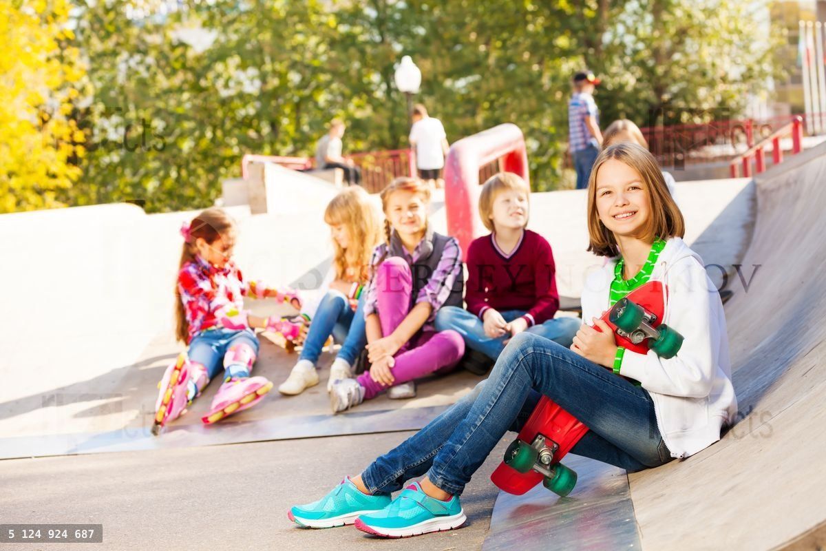 Girl with skateboard and her mates sitting