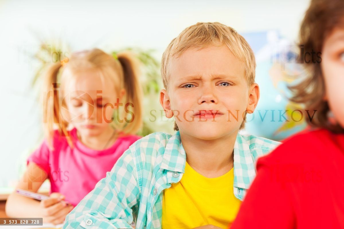 Frowning boy looking straight in classroom