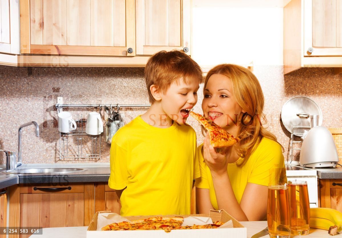Boy biting pizza from his mum's hand