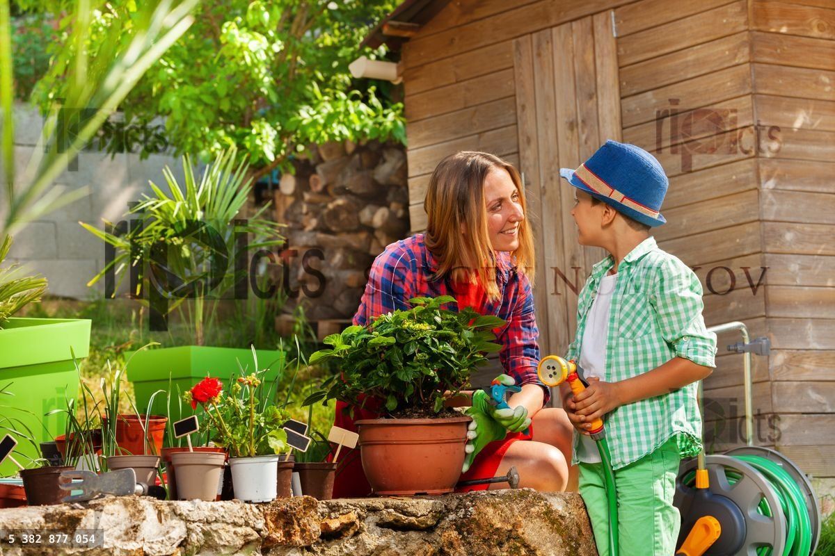 Young mother and her son watering plants outdoors