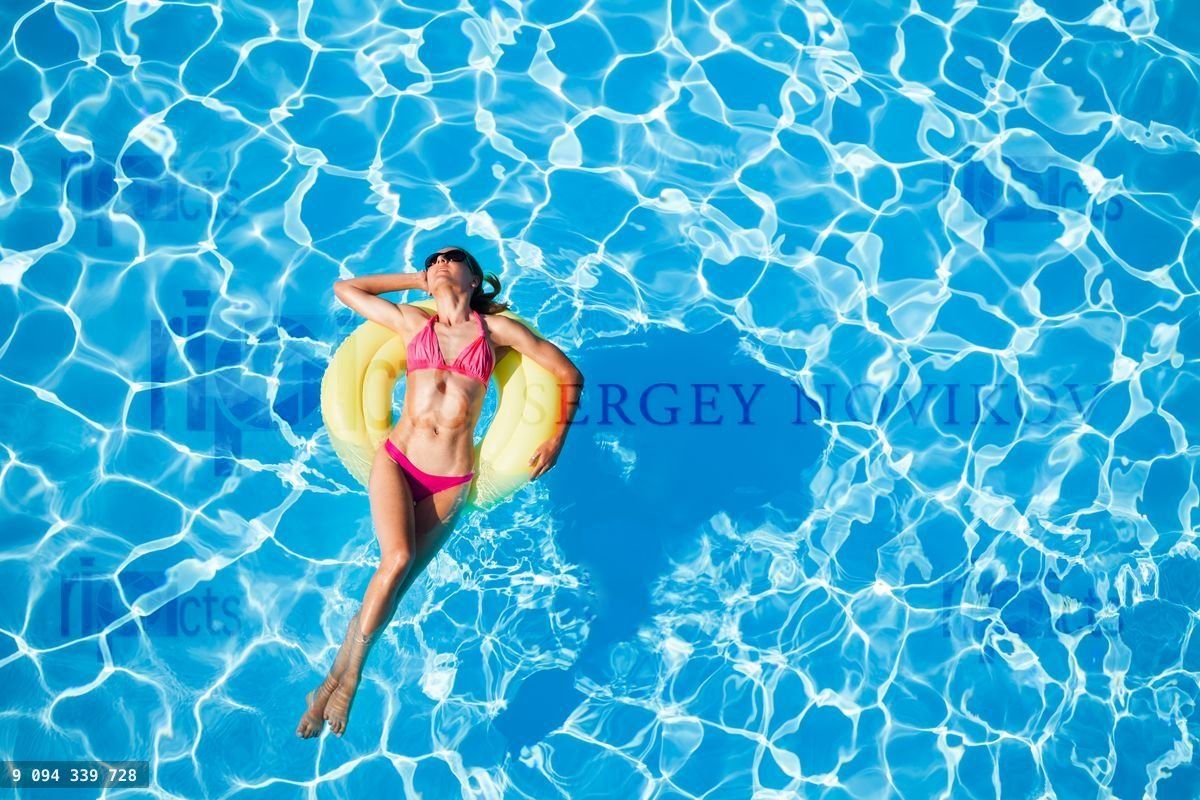 Woman sunbathing on yellow rubber ring in the pool
