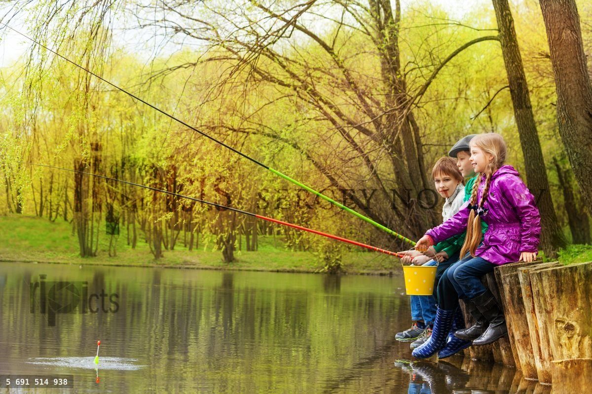 Children sitting and fishing together near pond