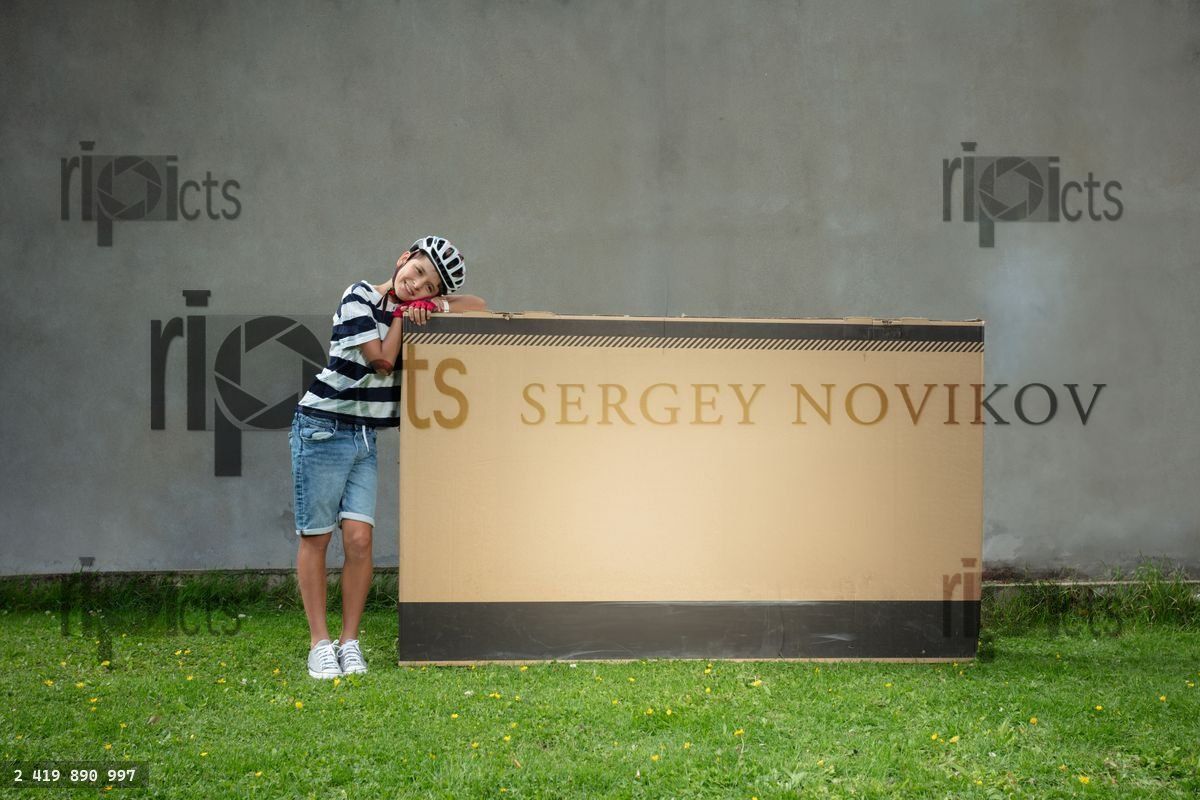 Young boy in striped shirt and shorts lean a large cardboard box
