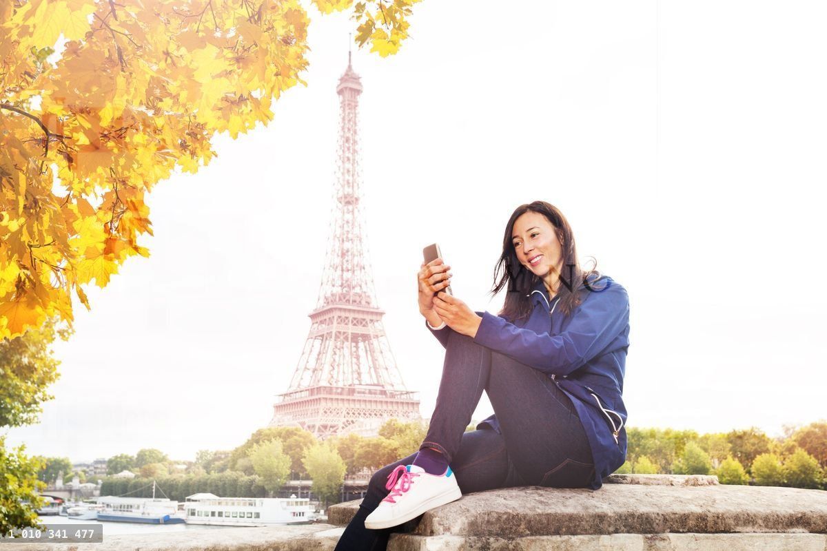 Woman texting on phone against the Eiffel Tower