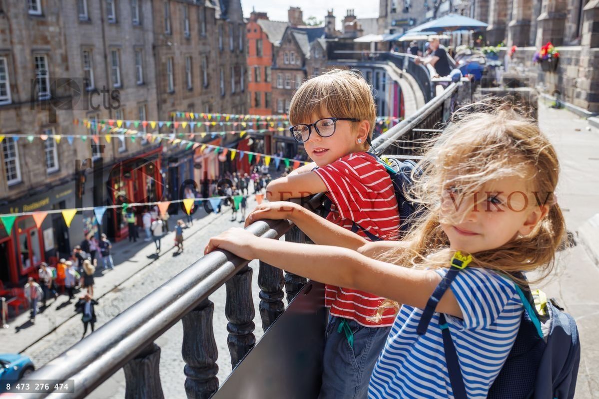 Two children, enjoy Victoria view from a balcony in Edinburgh