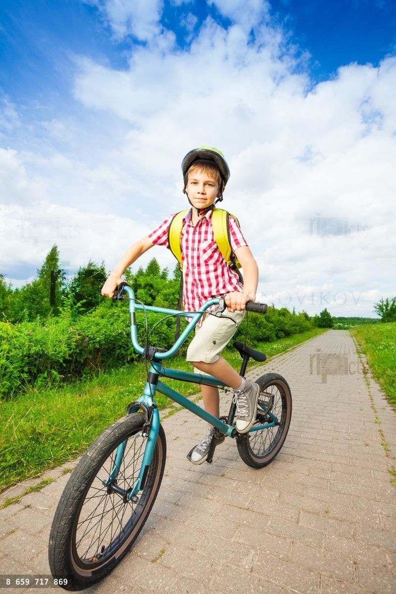 Boy in helmet rides his bike along the road