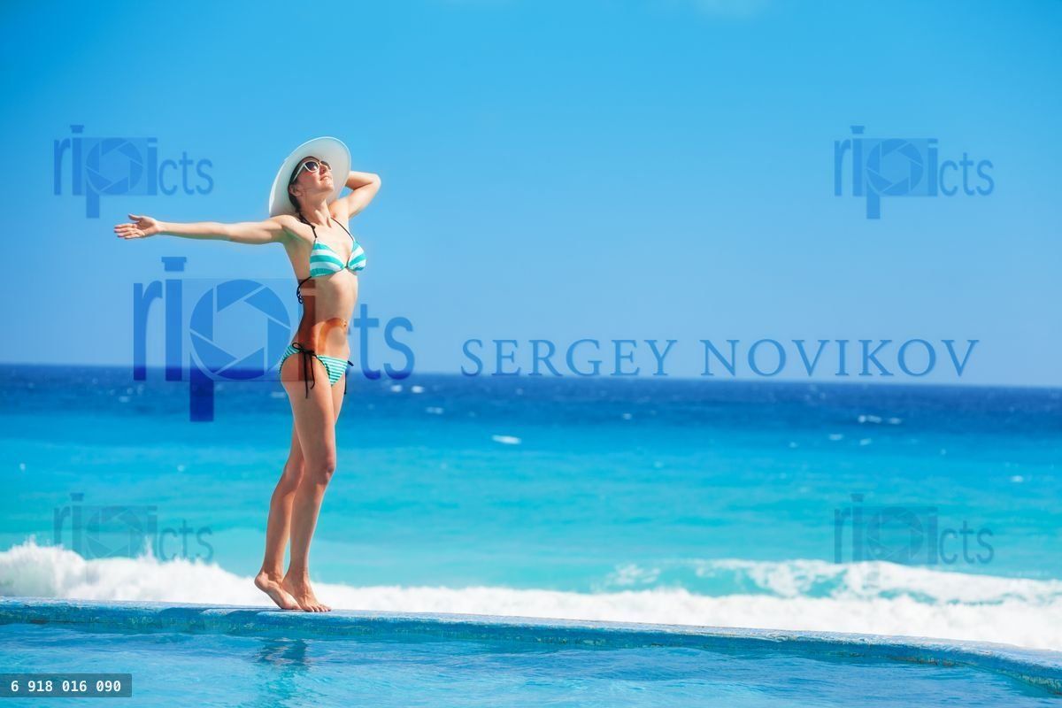 Woman standing with white hat on the ocean coast