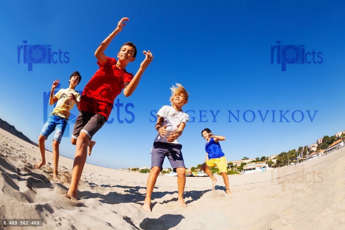 Four happy boys dancing on the beach in summer