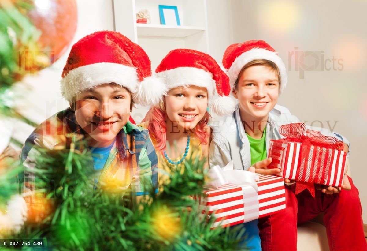 Cute teen children with presents by Christmas tree