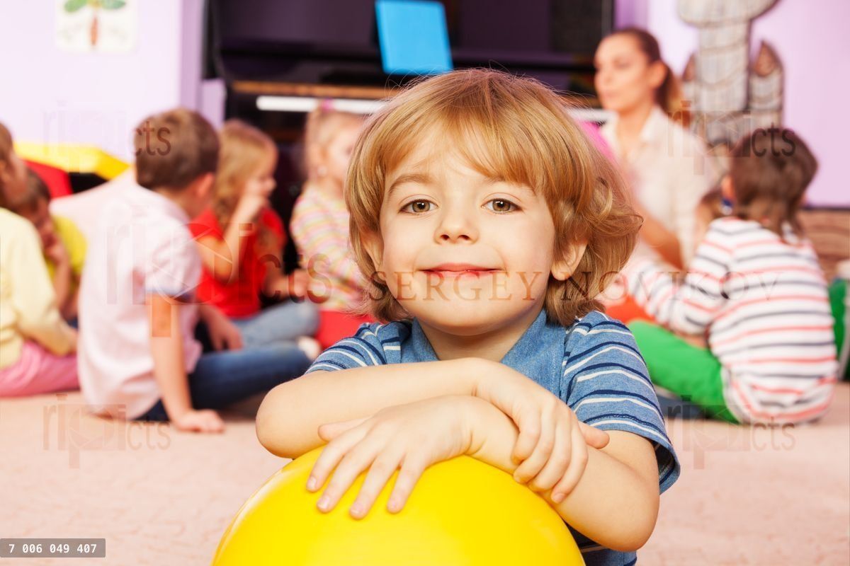 Happy boy with ball smiling and friends behind