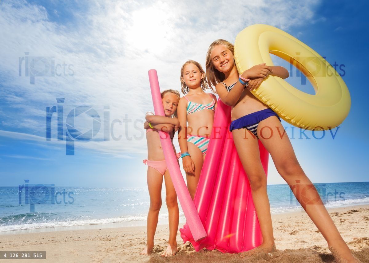 Funny girls with colorful swimming tools on beach