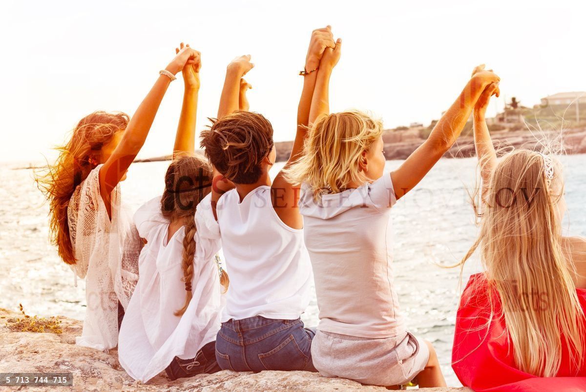 Friends holding hands and looking at the seascape