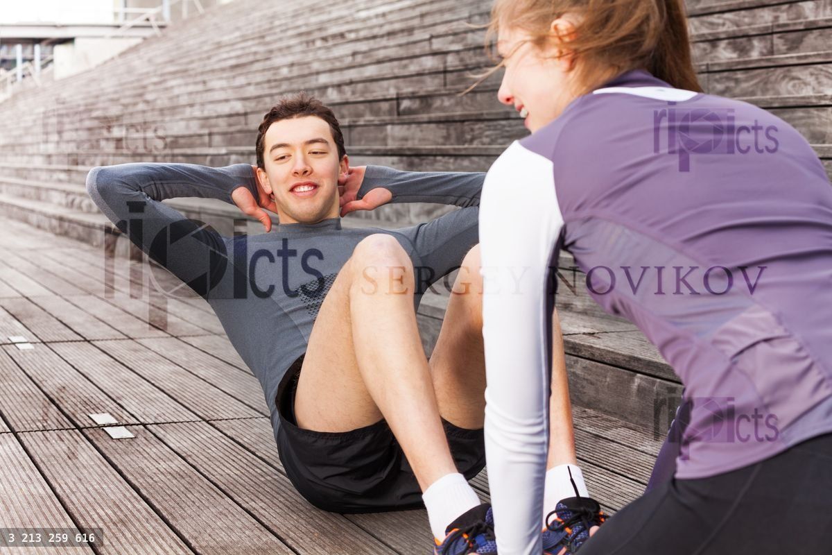 Young man making abs exercises outdoors with coach