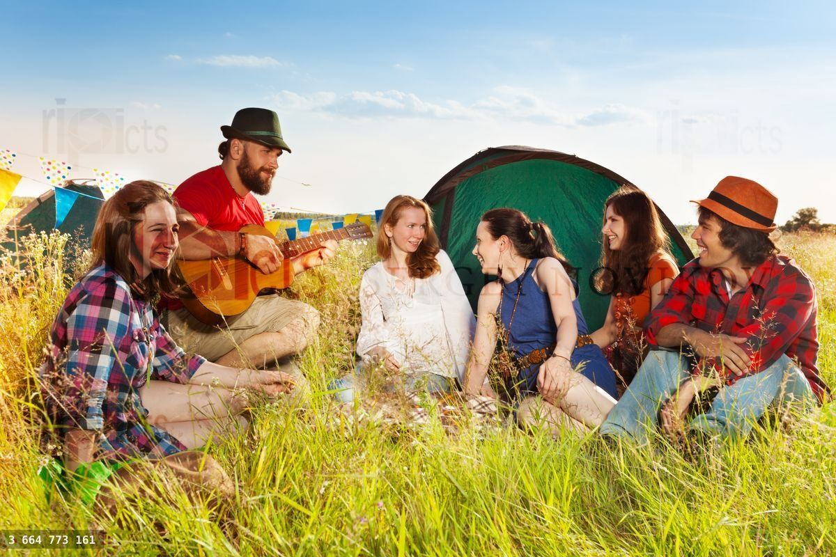 Young people singing to the guitar at campsite