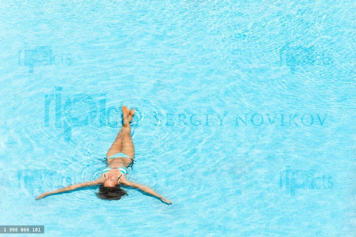 Young woman swimming in the crystal clear pool