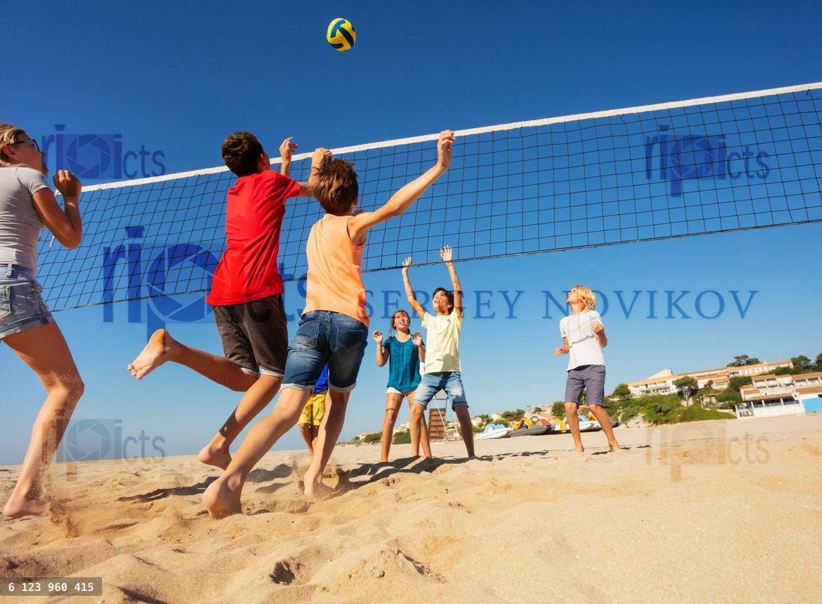Boys and girls playing volleyball on the beach