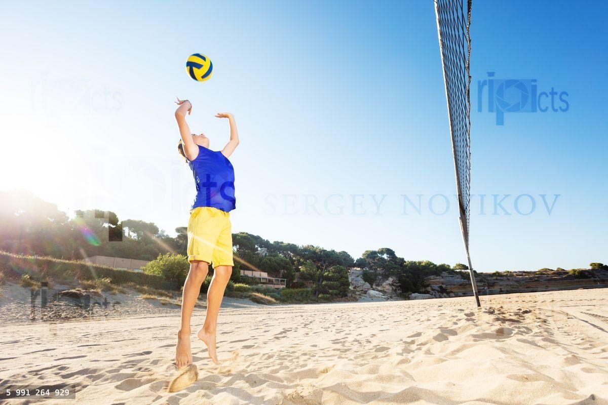 Young volleyball player jump serving on the beach