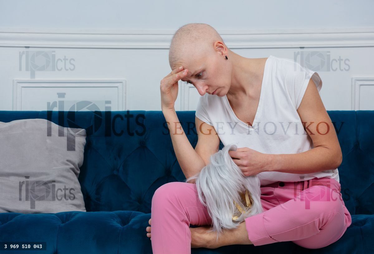 Woman coping with hair loss after chemo, sad hold wig in hands