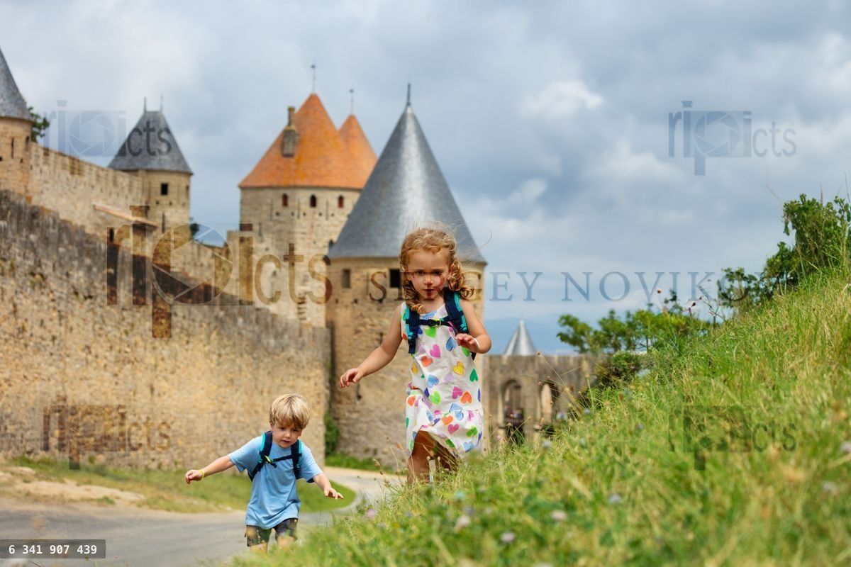 Young adventurers run hill in Carcassonne medieval fortress