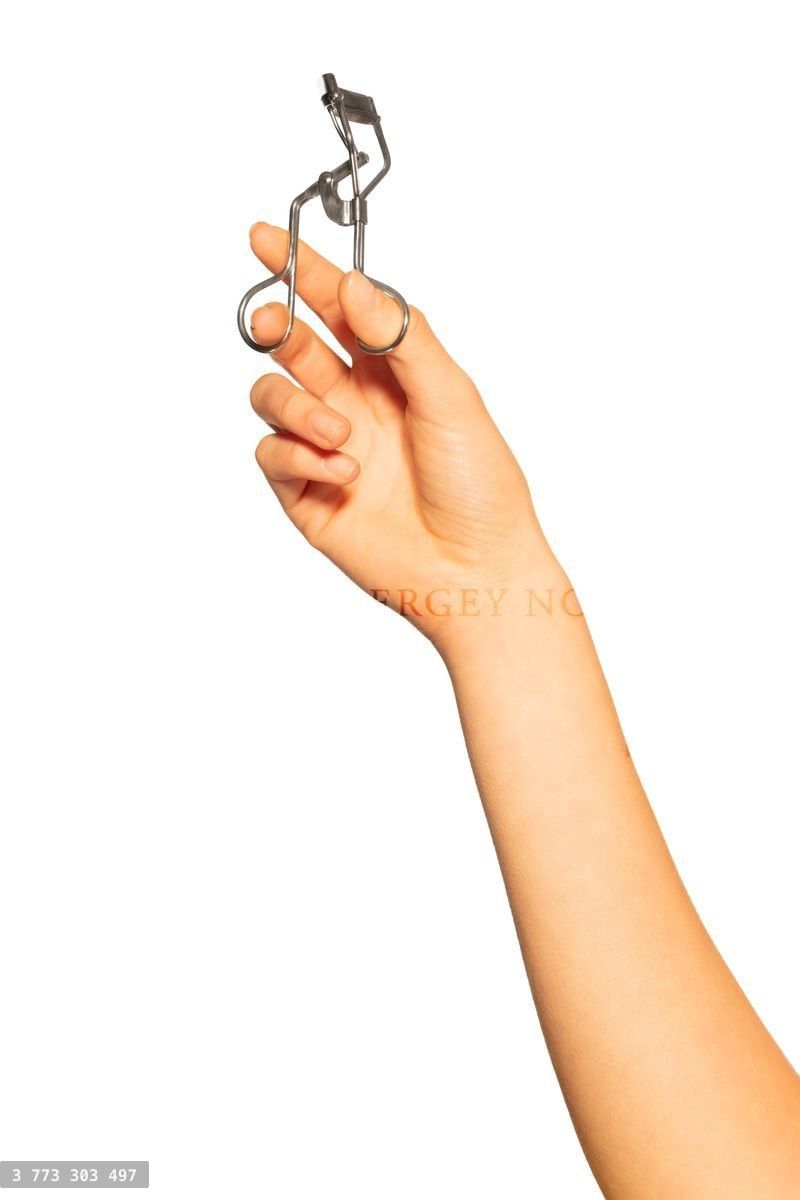 Woman's hand holding eyelash curler on white