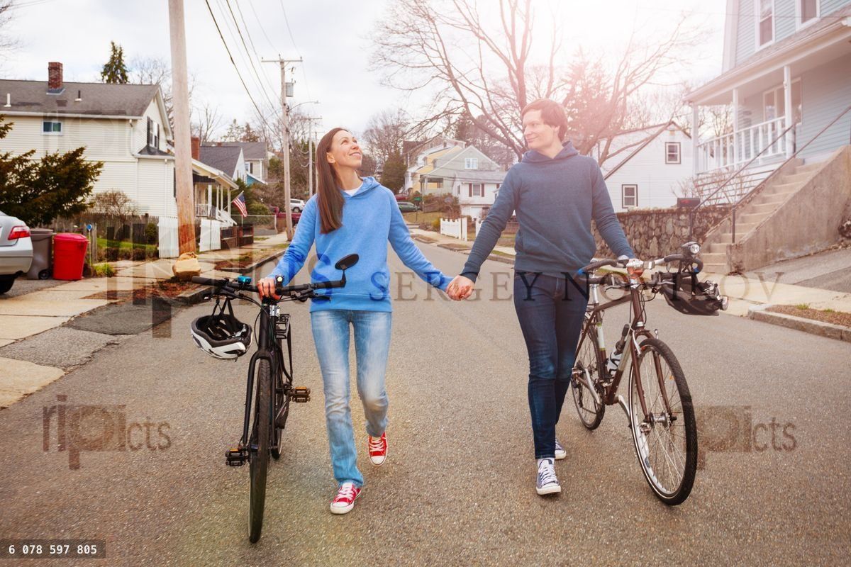 Young nice couple walk holding hands with bicycles