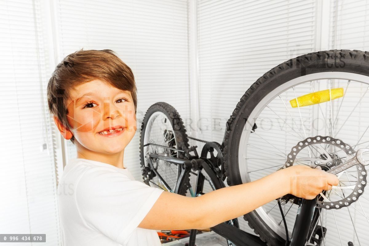 Happy boy repairing his bicycle wheel with spanner