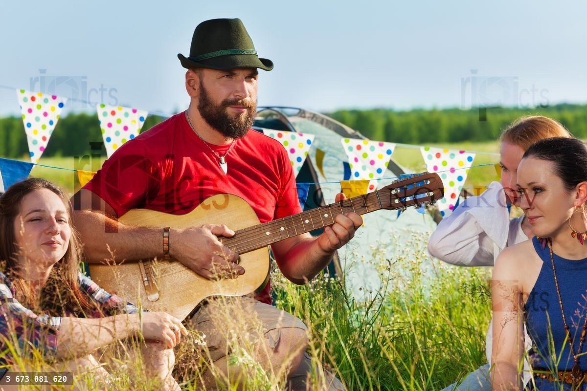 Young man playing guitar for his friends in camp