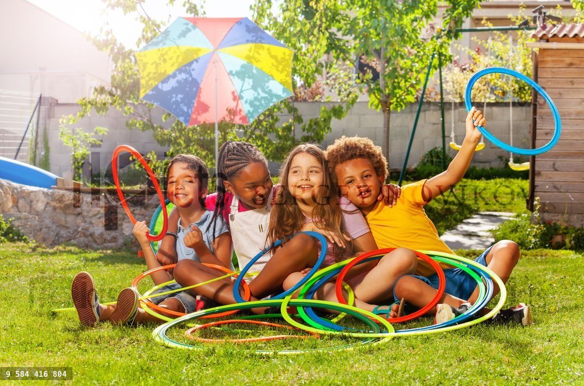Four kids in a group sit with hula hoops on lawn