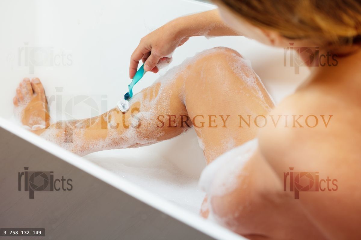 Woman shave leg sitting in bath with foam