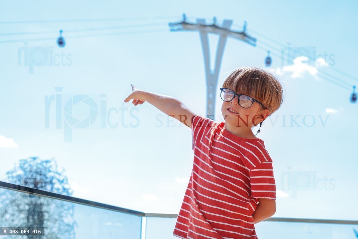 Young boy in glasses, pointing at gondolas, Greenwich, London