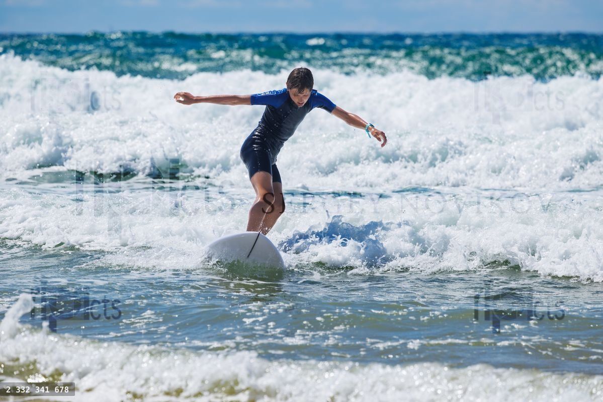 Young surfer teenager riding a wave at the beach during summer