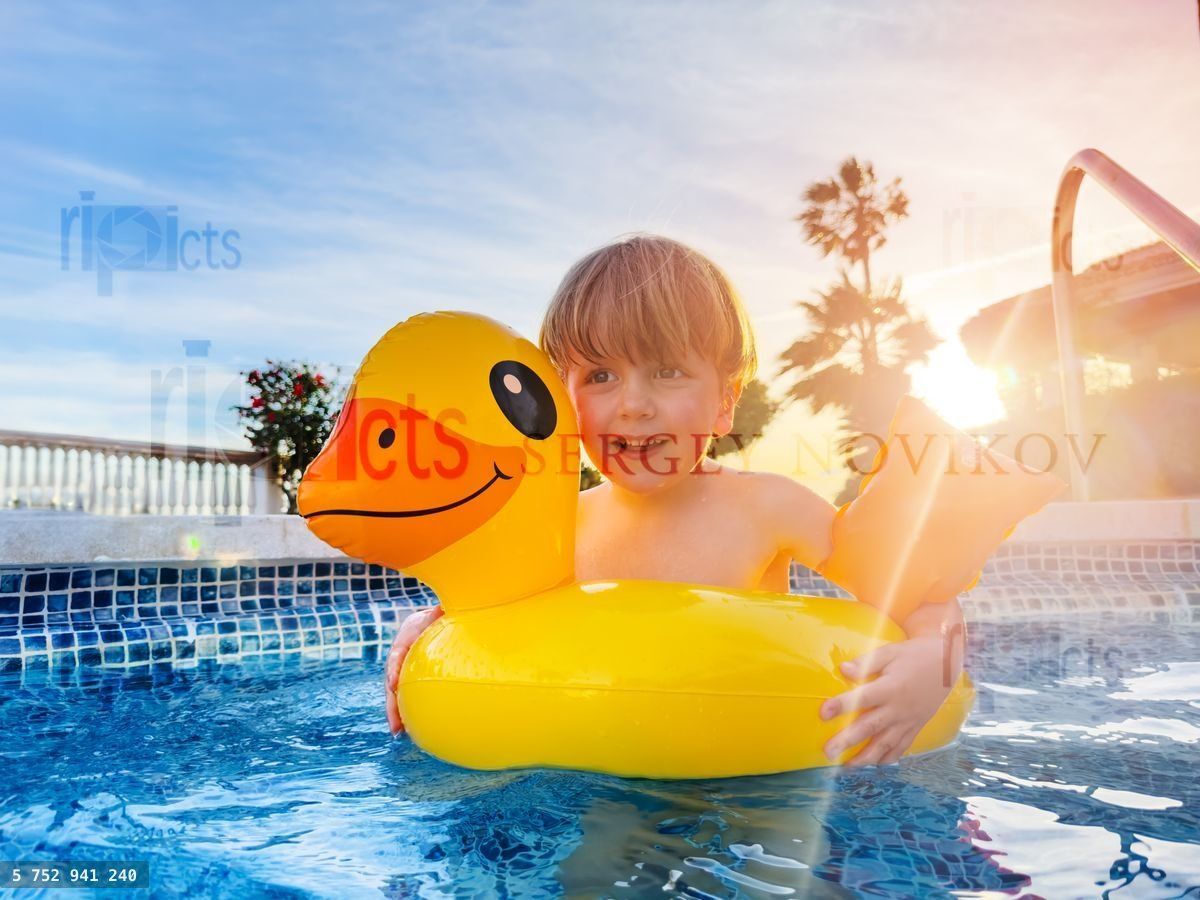 Happy boy with funny duckling buoy and floaties in pool