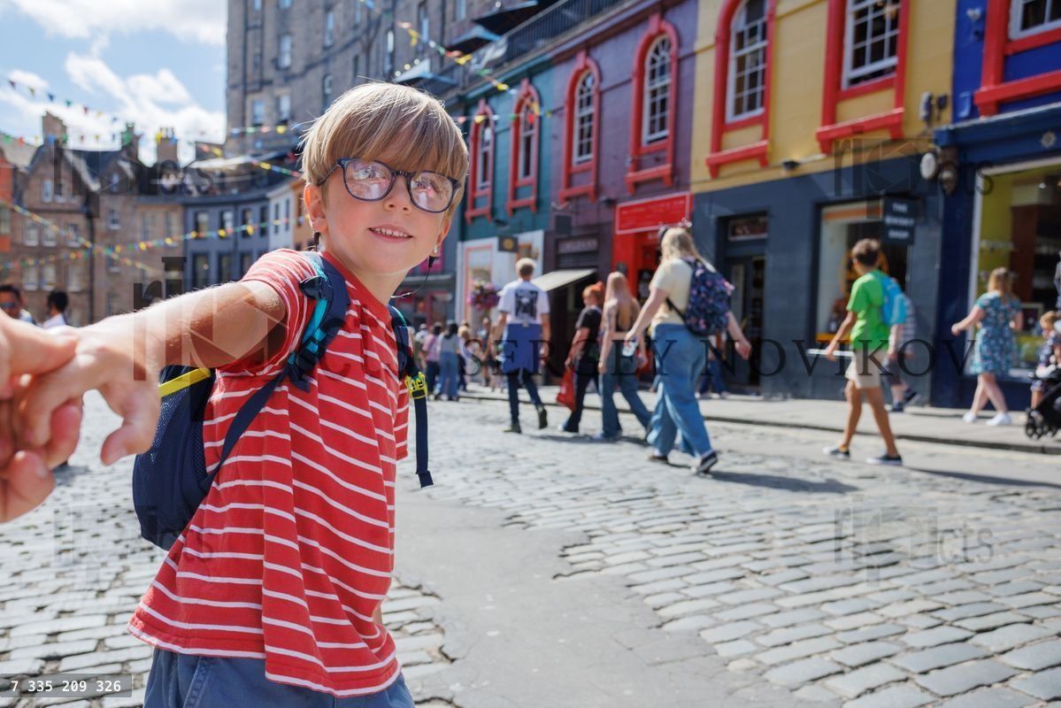 Young boy holds hand, walking through colorful, Victoria street