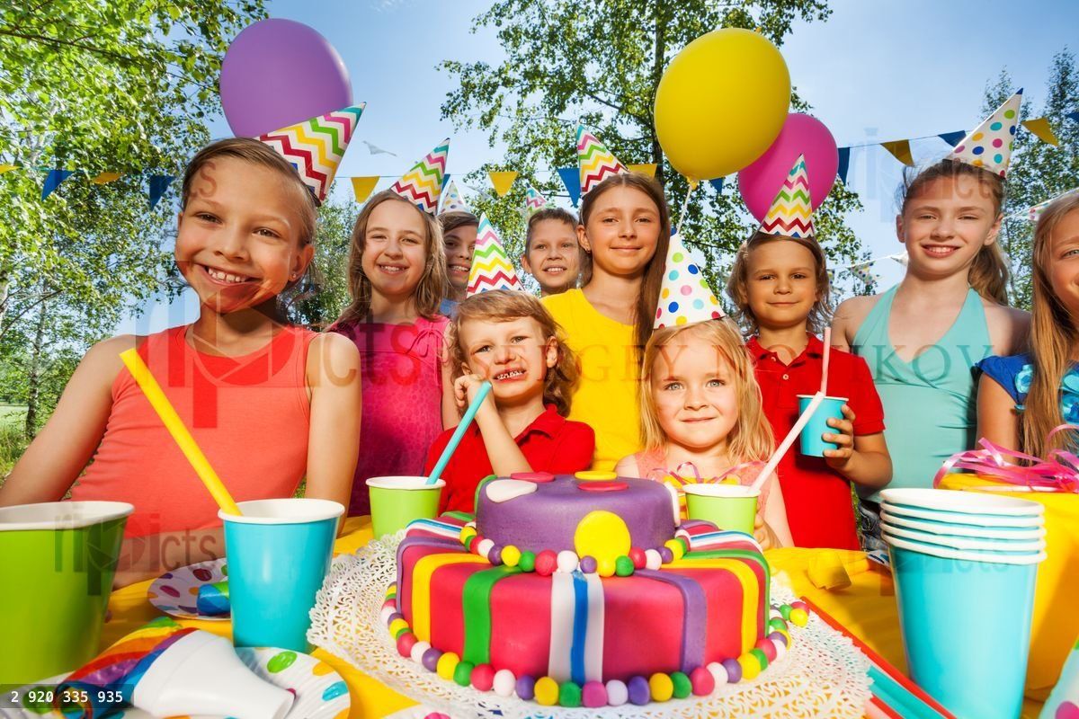 Big group of happy kids standing around B day cake