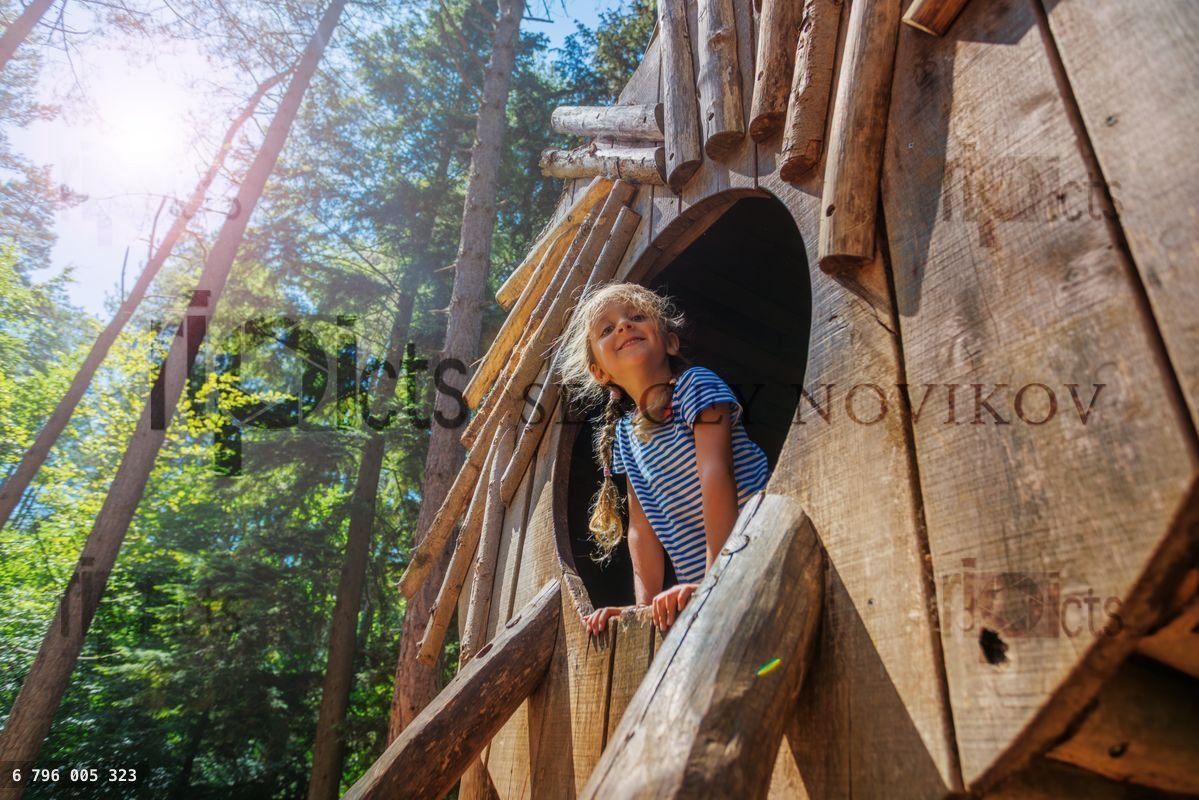 Young girl enjoying fun adventure in treehouse at sunny forest