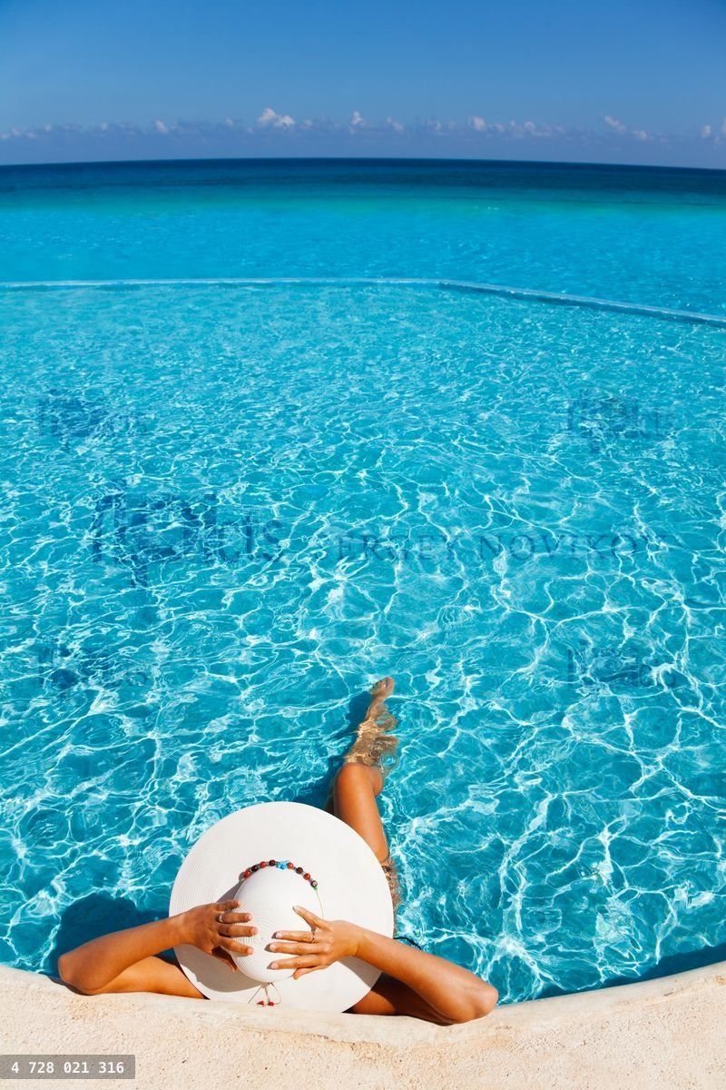 Woman holds white hat with hands laying in water